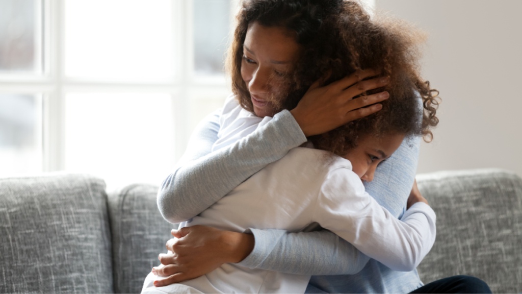 Mother and daughter hugging on a sofa